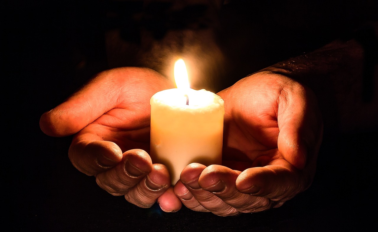 Hoffnung und Glück: Symbolisiert durch eine brennende Kerze in Handschalen