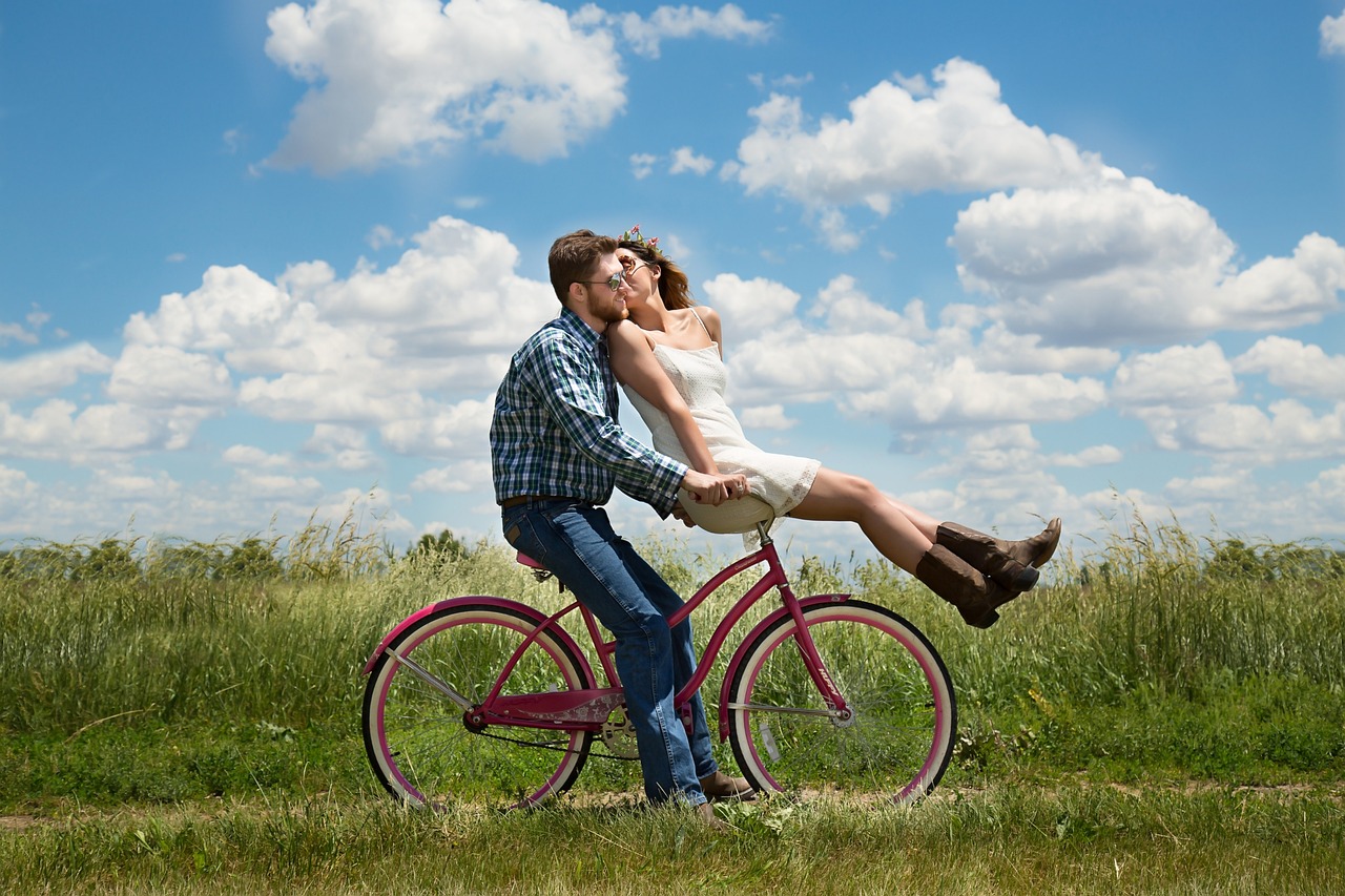 Glück ist ... ausgewählte Antworten. Romantisches Paar fährt auf einem Feldweg Rad.